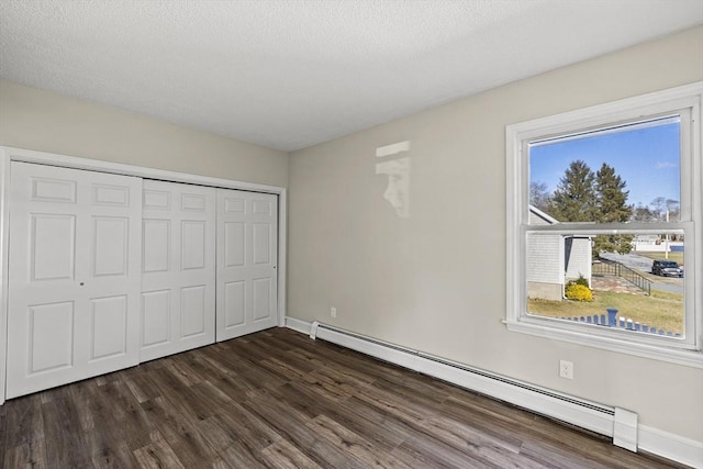 unfurnished bedroom with dark hardwood / wood-style flooring, a baseboard radiator, and a closet