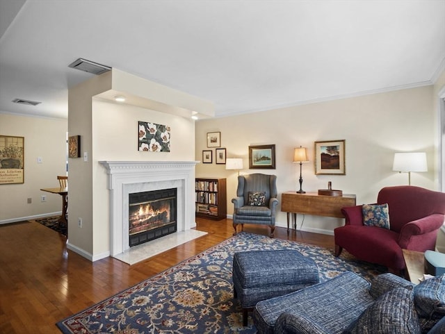 living room featuring visible vents, wood-type flooring, ornamental molding, and a high end fireplace