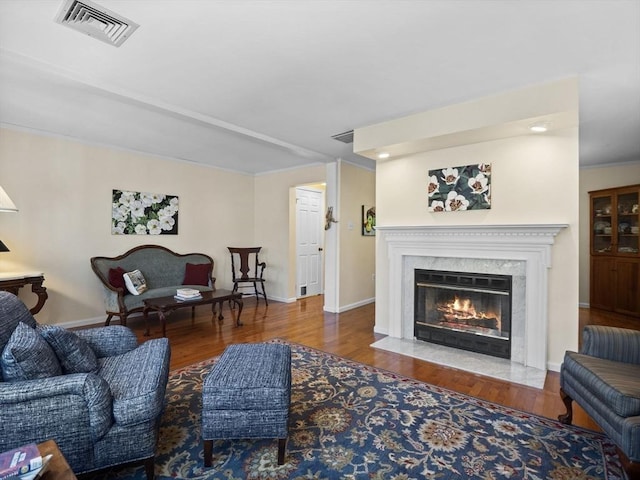 living area featuring visible vents, wood finished floors, baseboards, and a premium fireplace