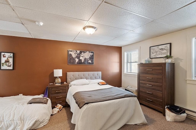 carpeted bedroom featuring a drop ceiling