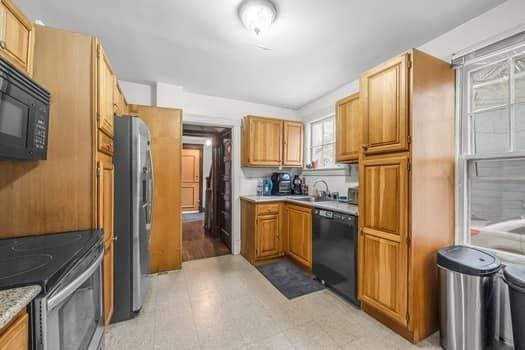 90 Rochelle St, Springfield, MA 01109 - kitchen featuring a sink, light countertops, brown cabinetry, black appliances, and light floors