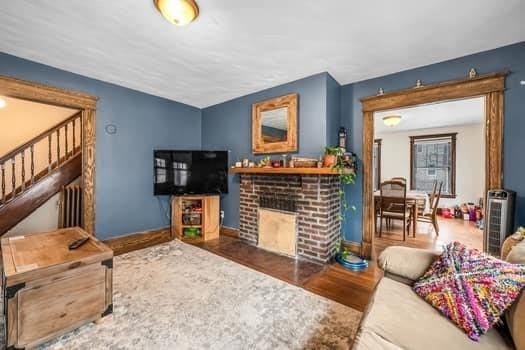 90 Rochelle St, Springfield, MA 01109 - living room with wood finished floors, baseboards, a brick fireplace, and stairway