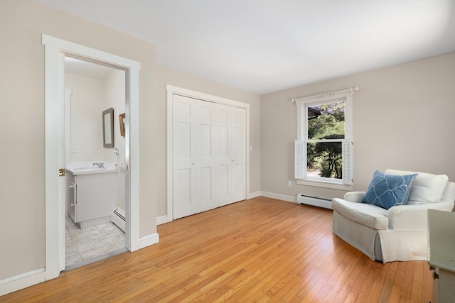 sitting room featuring sink, light hardwood / wood-style flooring, and a baseboard radiator