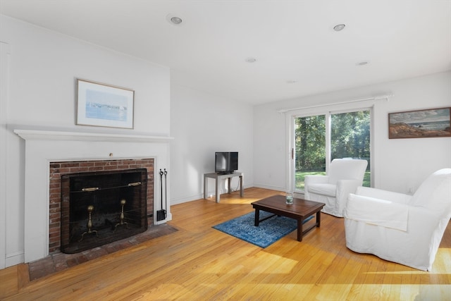 living room with wood-type flooring and a brick fireplace