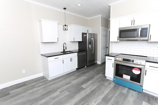 kitchen with appliances with stainless steel finishes, sink, white cabinets, hanging light fixtures, and crown molding