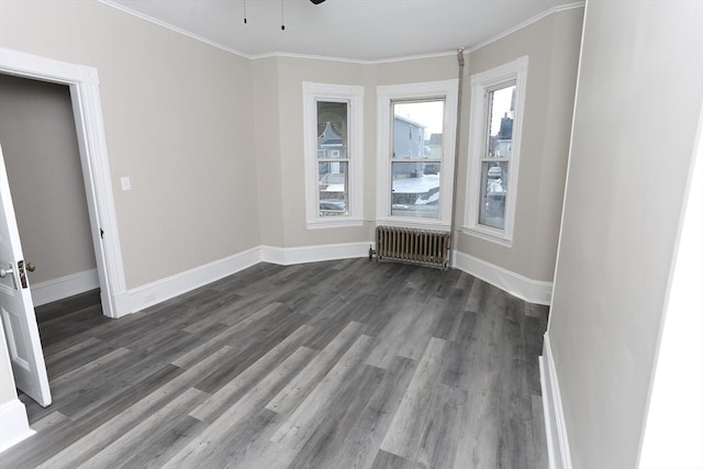 empty room featuring radiator, dark wood-type flooring, ornamental molding, and ceiling fan