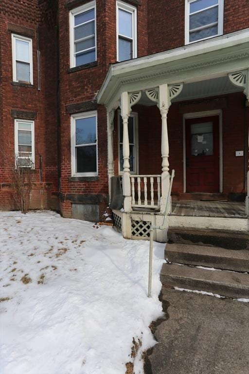 snow covered property entrance with covered porch