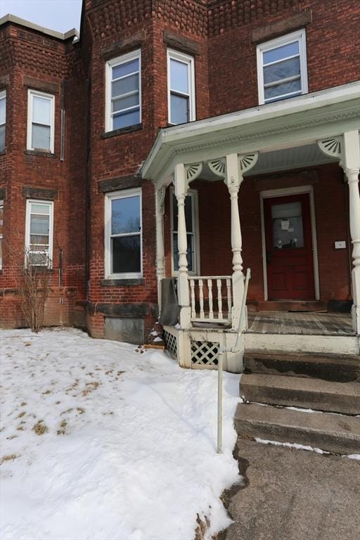 snow covered property entrance featuring a porch