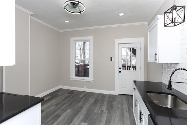 kitchen featuring sink, ornamental molding, white cabinets, pendant lighting, and backsplash