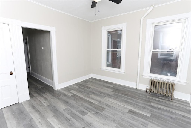 empty room featuring crown molding, ceiling fan, radiator, and hardwood / wood-style floors