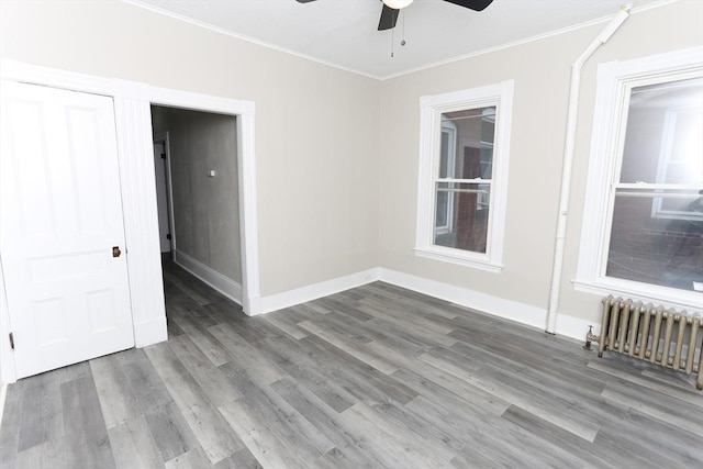 empty room featuring radiator, crown molding, hardwood / wood-style floors, and ceiling fan