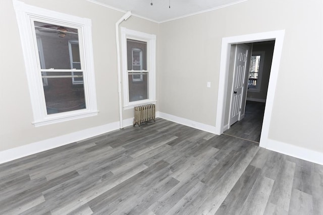 unfurnished room featuring crown molding, radiator, ceiling fan, and dark hardwood / wood-style flooring