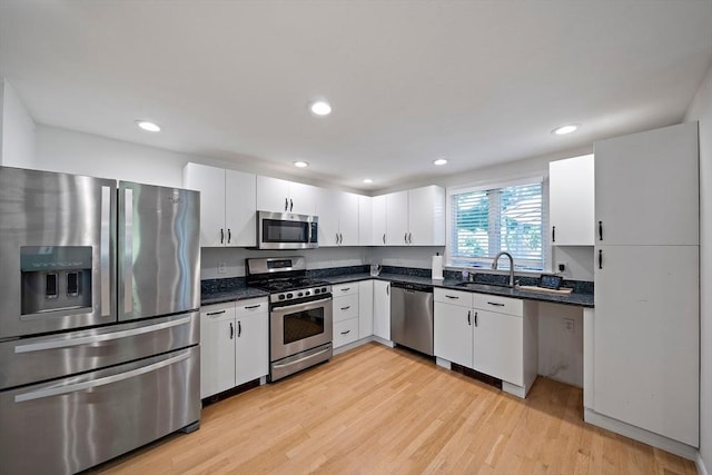 7 Helen Rd, Braintree, MA 02184 - kitchen featuring appliances with stainless steel finishes, white cabinets, light wood-style flooring, recessed lighting, and dark stone counters