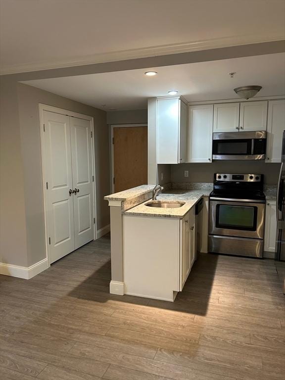 kitchen with sink, white cabinetry, kitchen peninsula, stainless steel appliances, and light stone countertops