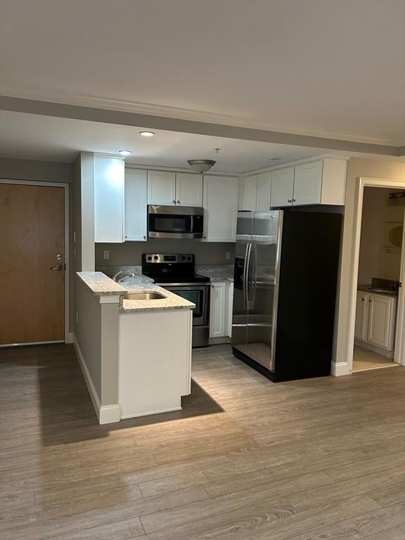 kitchen featuring light stone countertops, stainless steel appliances, light hardwood / wood-style floors, and white cabinets