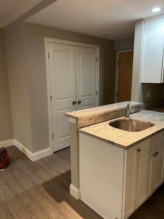 kitchen with light stone countertops, sink, white cabinets, and kitchen peninsula