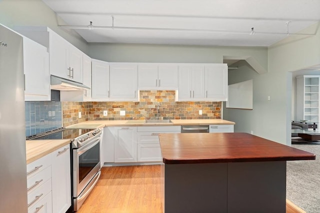 kitchen featuring white cabinets, decorative backsplash, stainless steel appliances, under cabinet range hood, and a sink