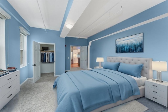 bedroom with light colored carpet, baseboards, a closet, freestanding refrigerator, and a walk in closet