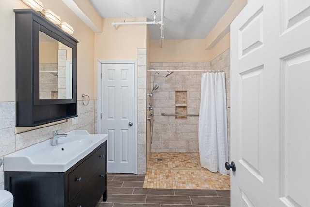 bathroom with wood tiled floor, tiled shower, tile walls, and vanity