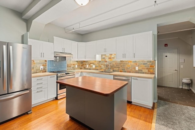 kitchen featuring wooden counters, appliances with stainless steel finishes, white cabinetry, a sink, and under cabinet range hood