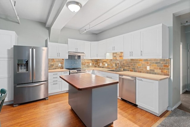 kitchen with light wood-type flooring, butcher block countertops, stainless steel appliances, and a sink