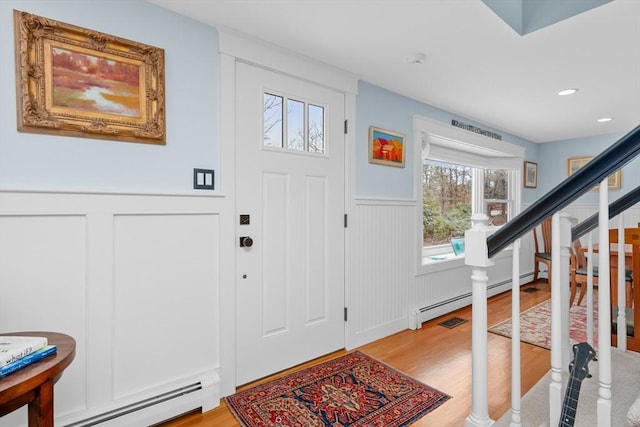 foyer with baseboard heating and light hardwood / wood-style flooring