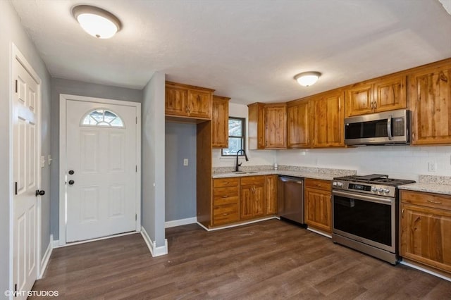 kitchen featuring light stone counters, sink, appliances with stainless steel finishes, and dark wood-type flooring