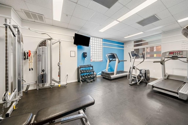 gym featuring a paneled ceiling and a healthy amount of sunlight