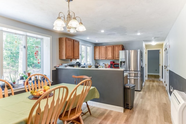 kitchen featuring pendant lighting, light hardwood / wood-style flooring, a chandelier, and stainless steel fridge with ice dispenser