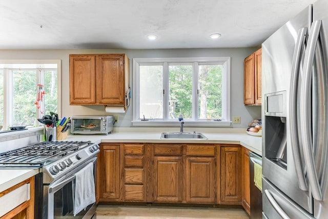 kitchen with light hardwood / wood-style floors, sink, stainless steel appliances, and plenty of natural light