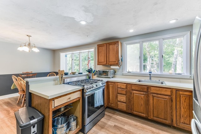 kitchen with decorative light fixtures, gas range, light wood-type flooring, and a wealth of natural light