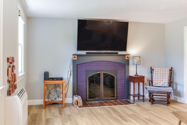 living room with a brick fireplace and light hardwood / wood-style floors