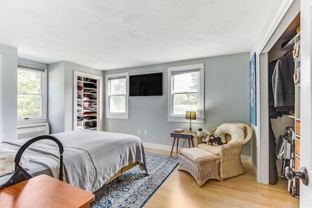 bedroom with light wood-type flooring, a closet, multiple windows, and a walk in closet