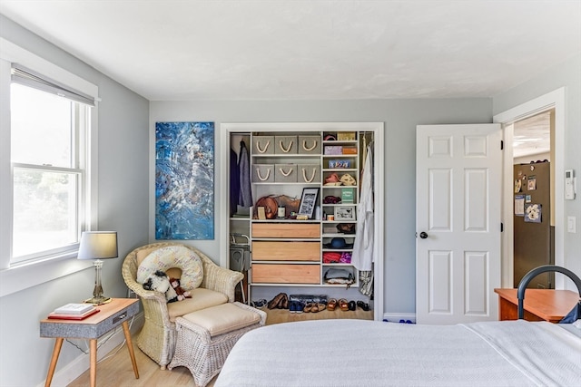 bedroom featuring multiple windows, wood-type flooring, and stainless steel refrigerator