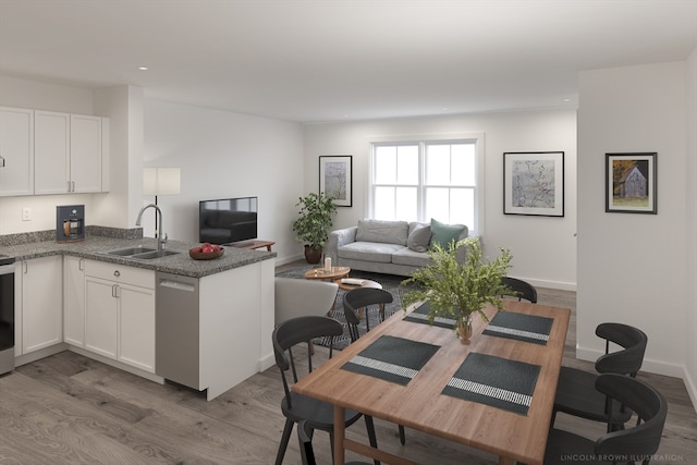 kitchen with dishwasher, white cabinetry, sink, and light hardwood / wood-style flooring