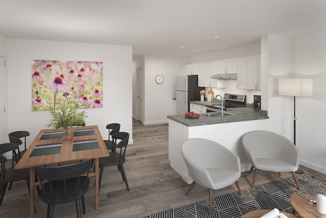 kitchen with appliances with stainless steel finishes, white cabinets, kitchen peninsula, hardwood / wood-style flooring, and sink