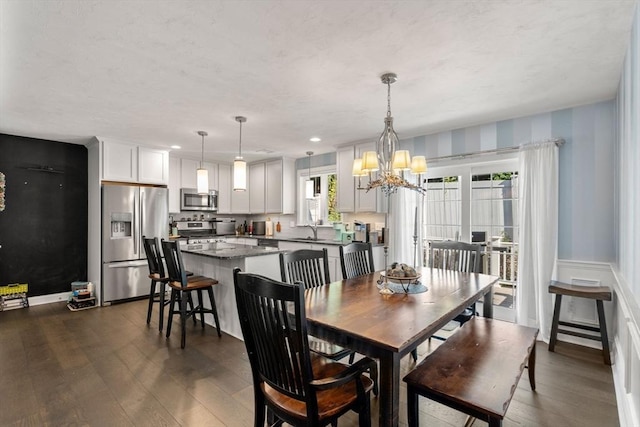 dining room with dark wood-type flooring, sink, and a notable chandelier