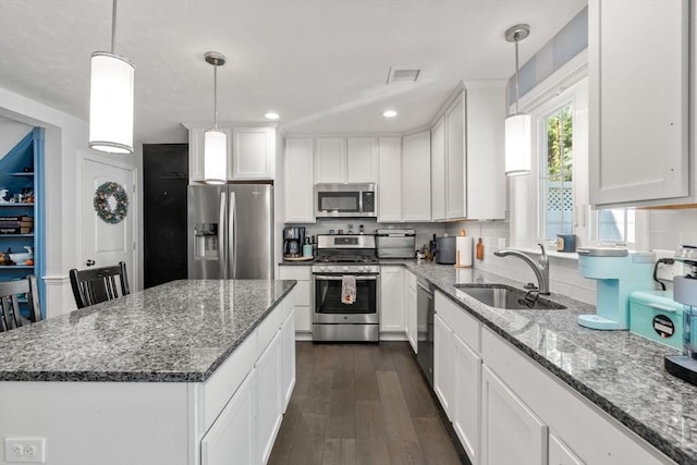 kitchen with appliances with stainless steel finishes, pendant lighting, and white cabinetry