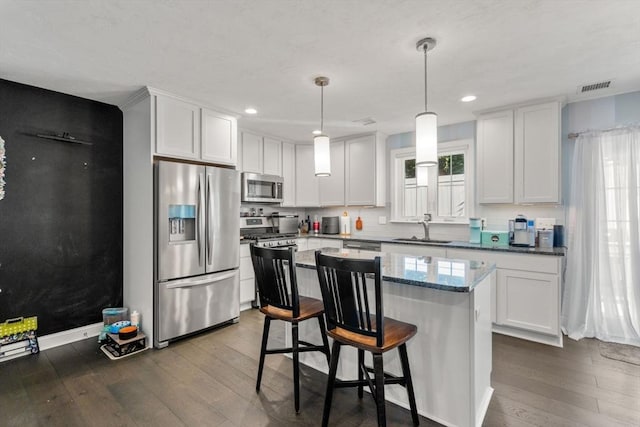 kitchen with stainless steel appliances, a center island, white cabinets, and decorative light fixtures