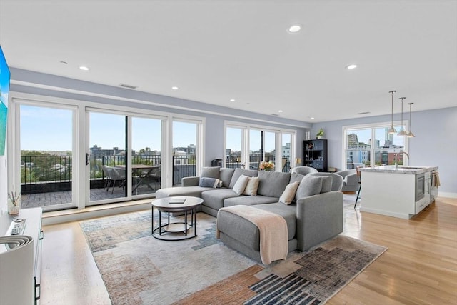 living room with light wood-style flooring, recessed lighting, a city view, and baseboards