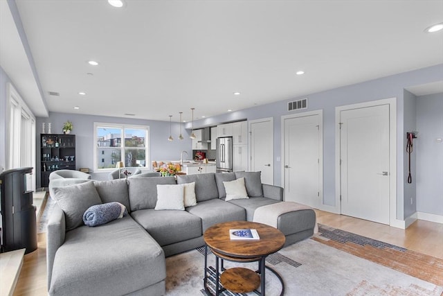 living room featuring recessed lighting, light wood-style floors, and baseboards