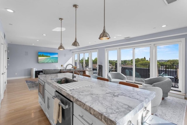kitchen featuring a sink, stainless steel appliances, open floor plan, white cabinets, and recessed lighting