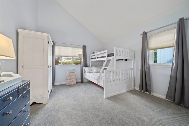 bedroom with lofted ceiling, multiple windows, and light colored carpet