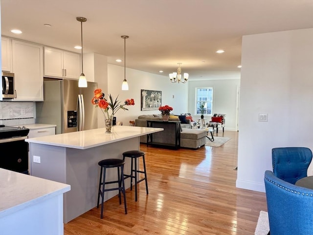 215 High St Unit 18, Taunton, MA 02780 - kitchen featuring light wood finished floors, stainless steel appliances, open floor plan, a chandelier, and a breakfast bar area