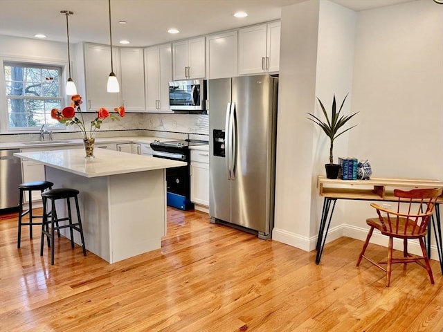 215 High St Unit 18, Taunton, MA 02780 - kitchen featuring light wood finished floors, a kitchen breakfast bar, light countertops, backsplash, and appliances with stainless steel finishes