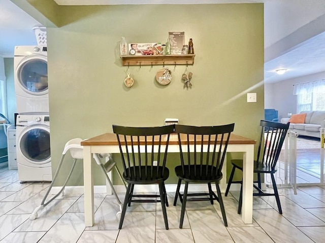 dining area with marble finish floor, stacked washer and clothes dryer, and baseboards