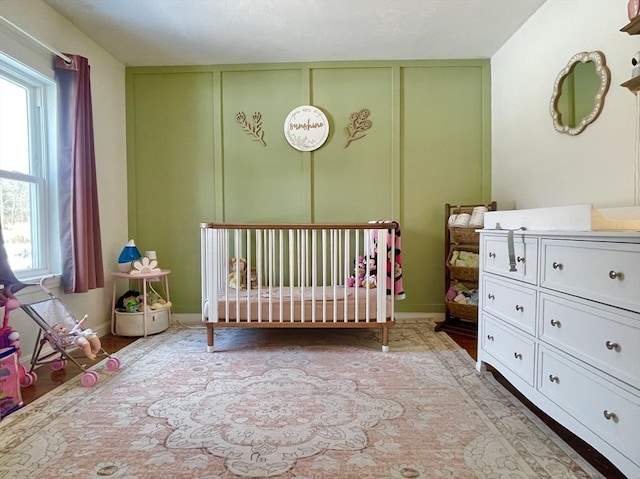 unfurnished bedroom with a nursery area and baseboards