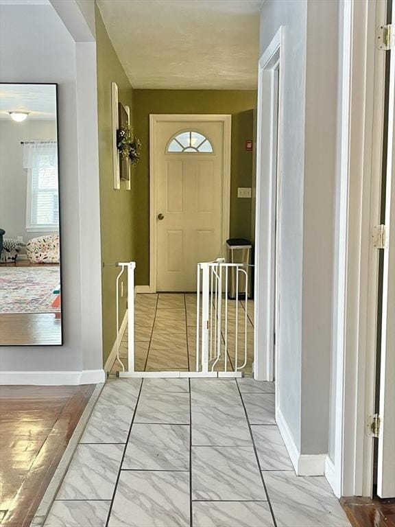 doorway with marble finish floor and baseboards