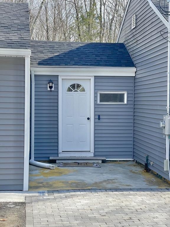 doorway to property with a shingled roof