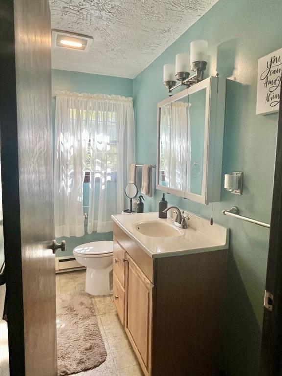 15 Old County Rd, Holland, MA 01521 - half bathroom featuring a textured ceiling, tile patterned flooring, vanity, a baseboard radiator, and toilet